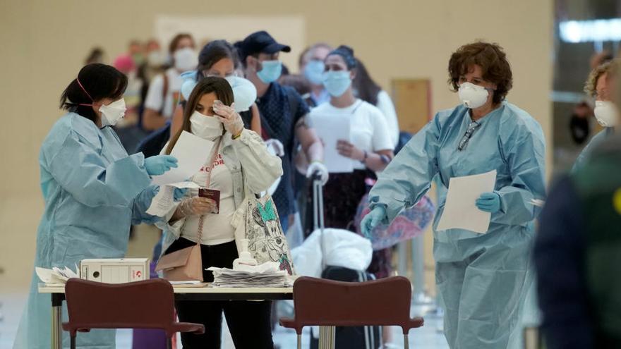 Varios trabajadores con guantes y mascarillas en el aeropuerto Madrid-Barajas.