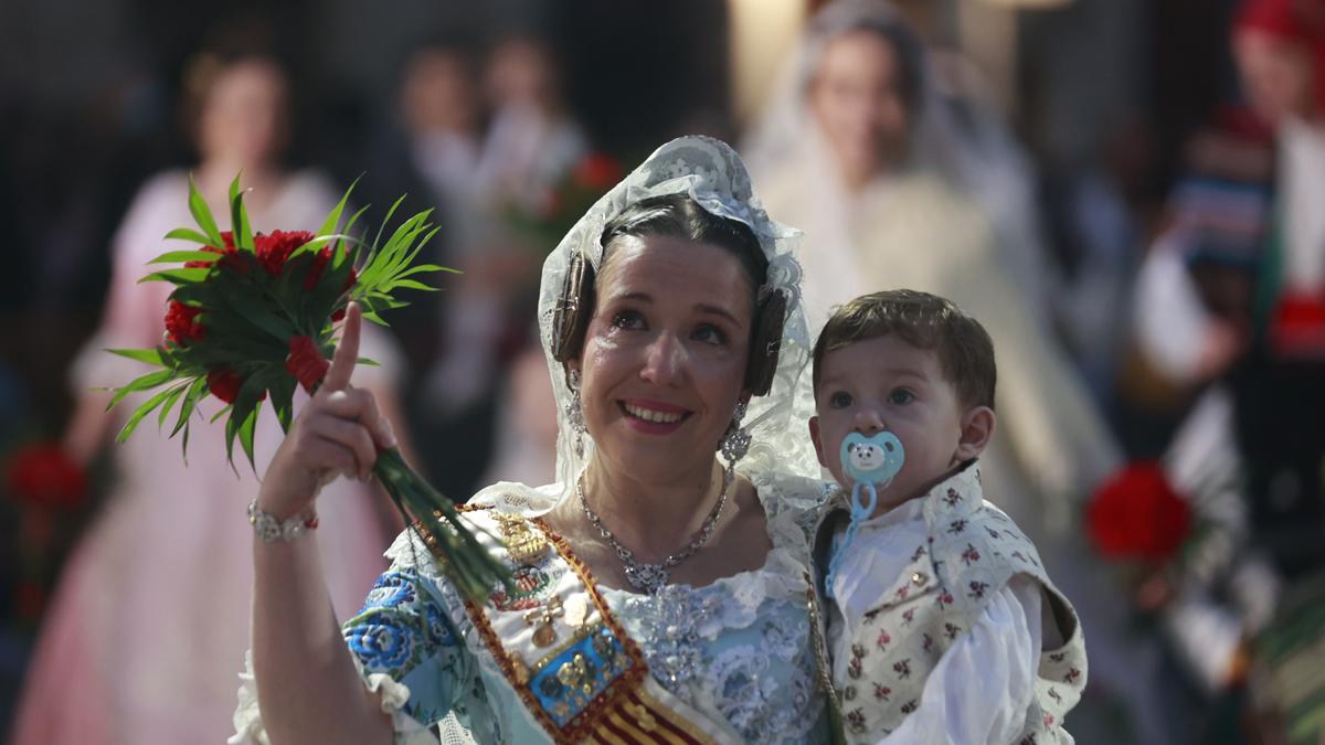 Una madre que porta a su hijo en brazos se emociona al ver a la virgen.