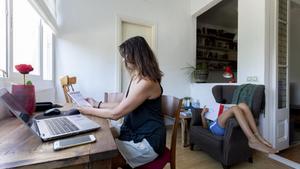 Imagen de archivo de una mujer teletrabajando con su hijo