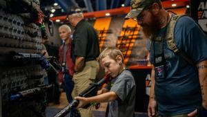 Un padre observa cómo su hijo sostiene un rifle AR-15 durante la convención de la Asociación Nacional del Rifle en Houston, este sábado.