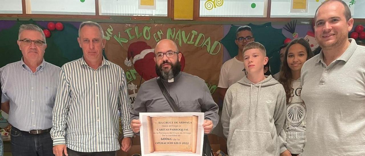 El alumnado y profesorado del IES Cruce de Arinaga posan con el sacerdote que sostiene un diploma que certifica la donación.