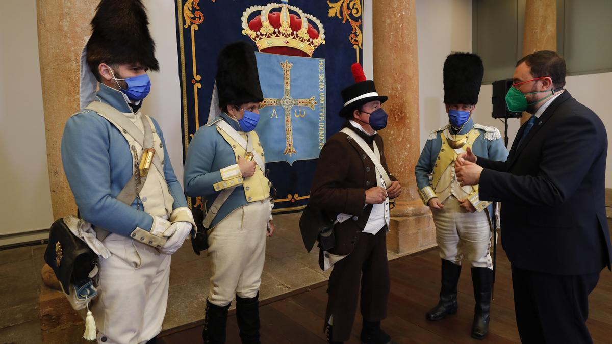 Adrián Barbón conversa con Secundino Pereira, presidente de Recreación Histórico Cultural de Asturias, junto a dos miembros de la misma asociación con uniformes de la Guardia de Honor de la Junta Suprema de Asturias.