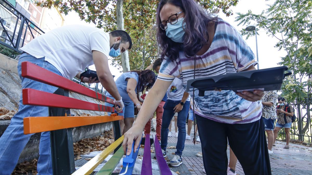 Activistas LGTBI junto con el alcalde cacereño, Luis Salaya, y el concejal David Holguín, se ponen manos a la obra con un banco.