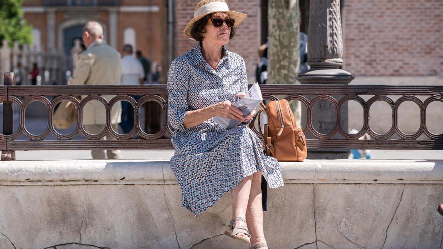 Una mujer mayor se protege del sol con sombrero y gafas durante la celebración del Festival de l Palabra, en la plaza de Cervantes, a 23 de abril de 2023, en Alcalá de Henares, Madrid, (España). Alcalá celebra el Día Internacional del Libro con una progra