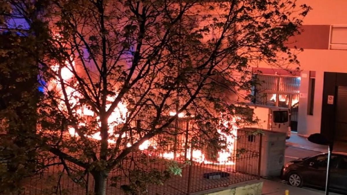 Arden varios contenedores y un coche en la calle Germanies de Xàtiva