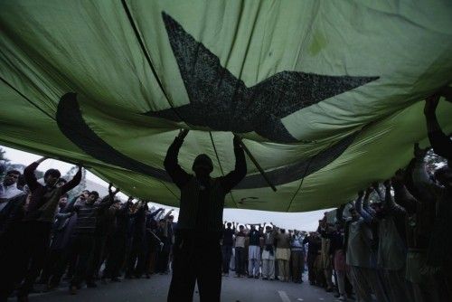 A supporter of Sufi cleric and leader of Minhaj-ul-Quran organisation Qadri stands under Pakistani flag during protests in Islamabad