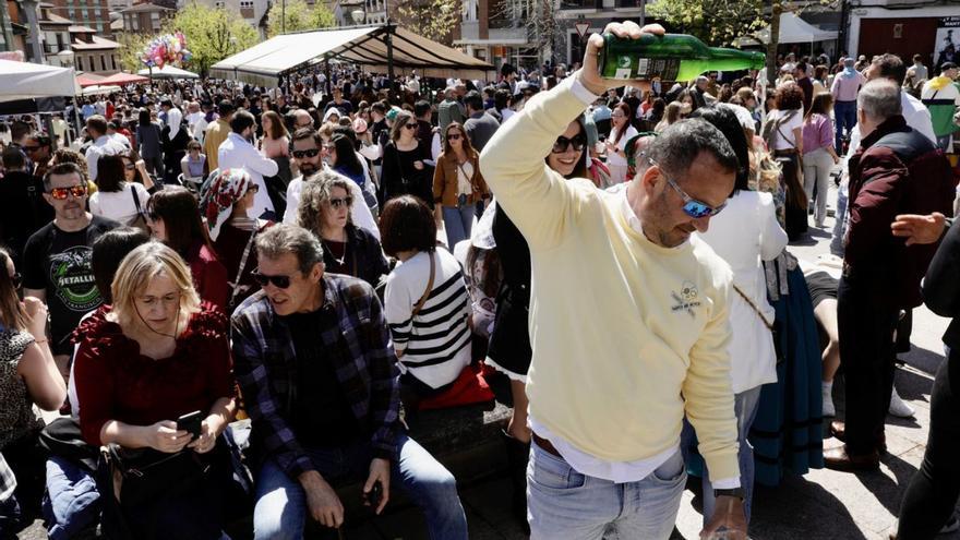 Un hombre escanciando a mediodía en la plaza de Les Campes, a rebosar. A la izquierda, la actuación de «París de Noia». | JUAN PLAZA