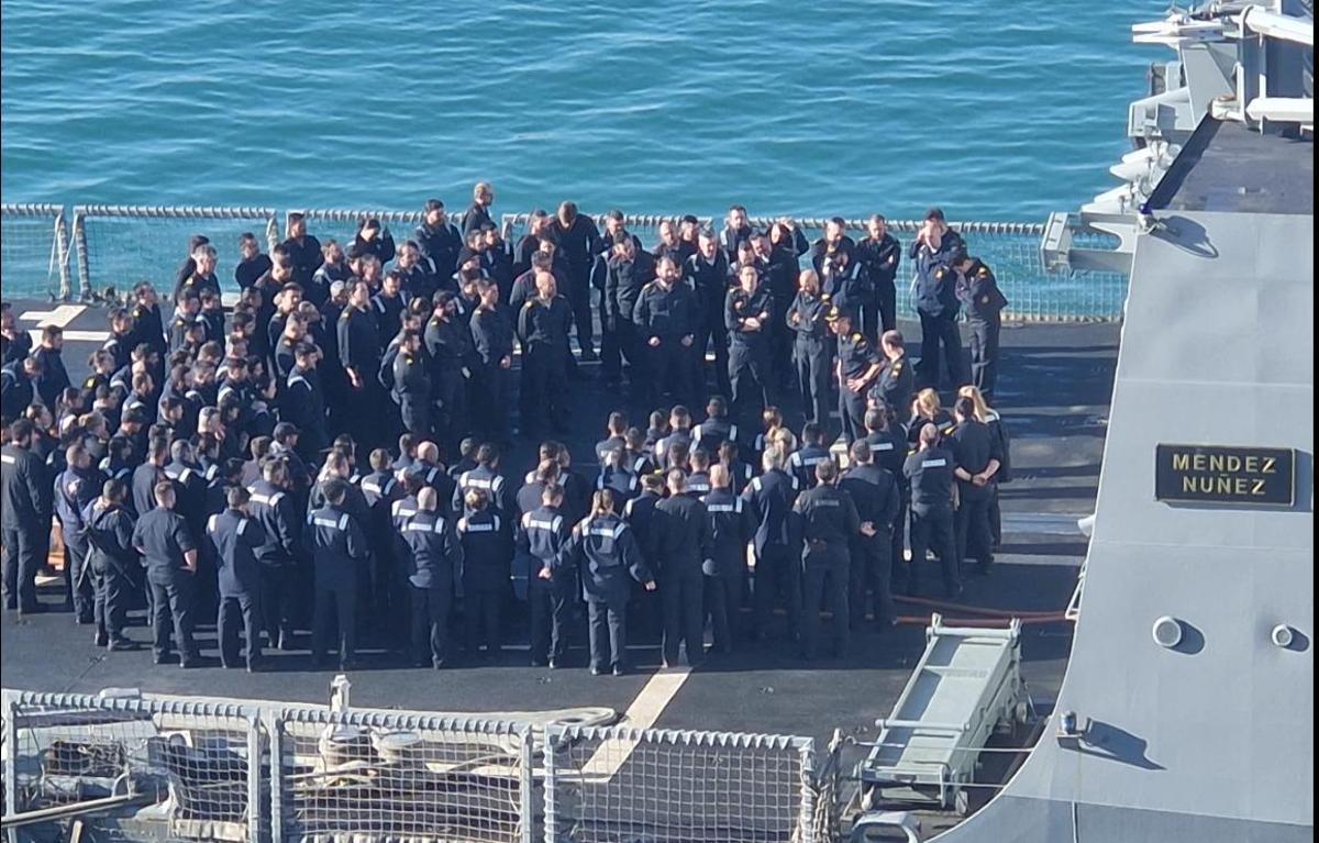 Reunión en cubierta de la dotación de la fragata Méndez Núñez. Los tripulantes hacen corro en torno al capitán, que les habla a la derecha, tocado con gorra.