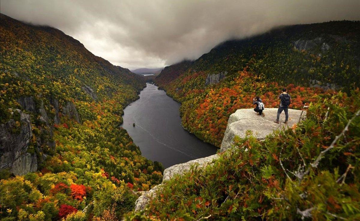 Dos visitantes fotografían el paisaje otoñal desde el mirador de Indian Head, sobre el lago Lower Ausable en Adirondacks, en el estado de Nueva York.