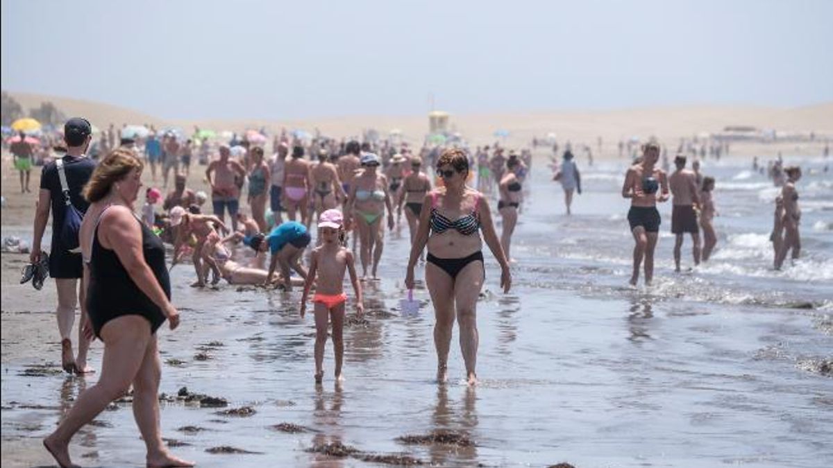 Turistas se refrescan en la orilla de la playa de Maspalomas.