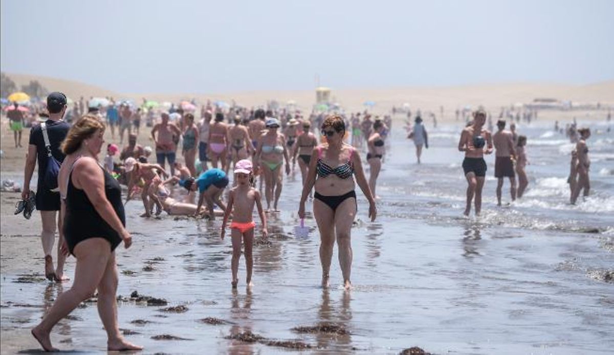 Turistas se refrescan en la orilla de la playa de Maspalomas.