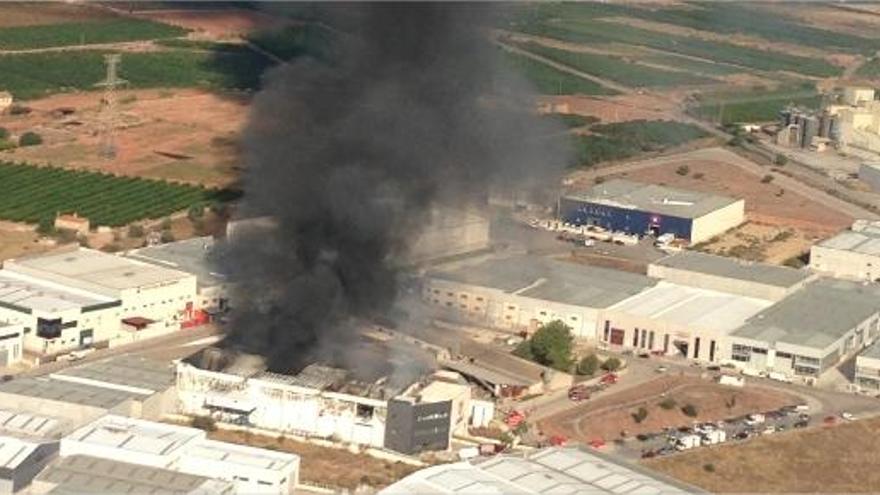 Los bomberos tratan de sofocar el incendio que destruyó el techo de una nave de frutos secos en un polígono de Náquera.