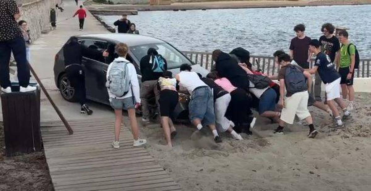 Varias personas empujan el Mercedes atrapado en Platja d'en Bossa.