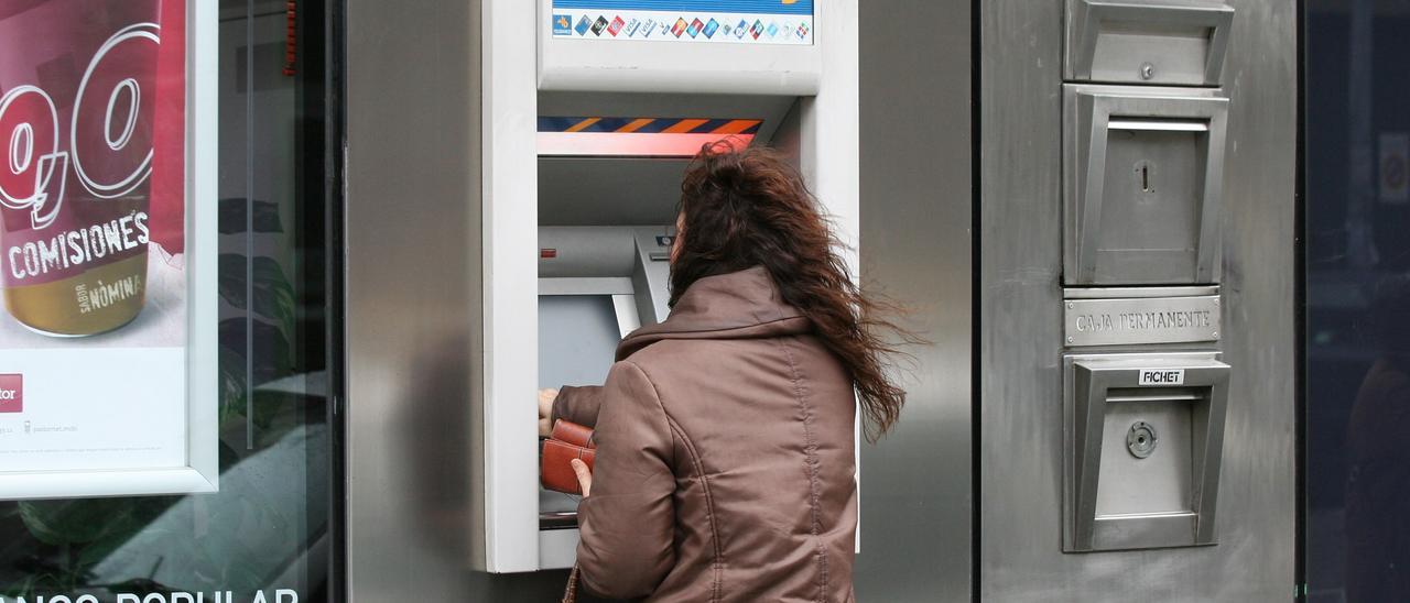 Una mujer retira dinero de un cajero automático
