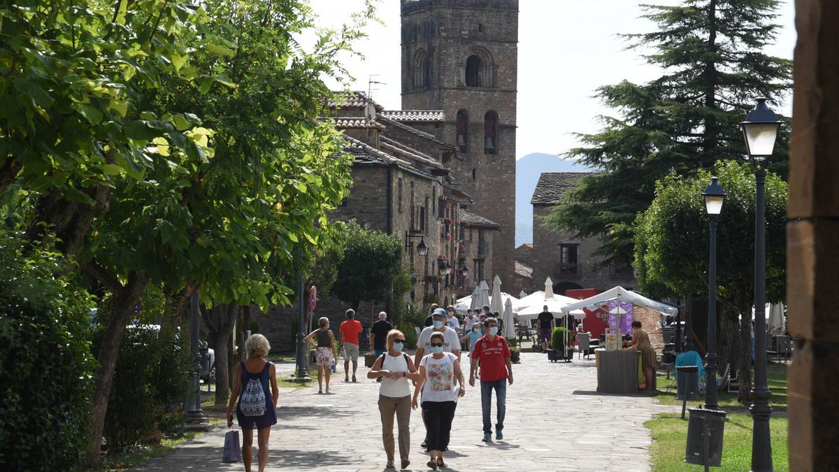 Varias personas caminan por el andador que conduce al castillo de Aínsa.