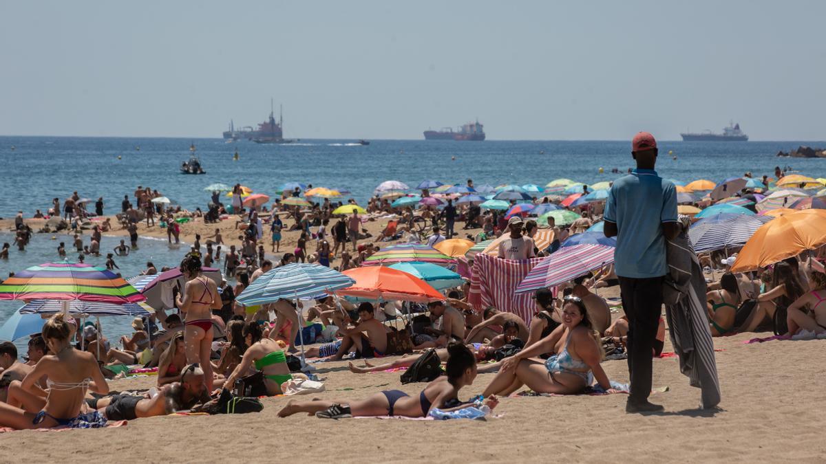 Cientos de personas disfrutan de la playa durante la ola de calor en Barcelona.