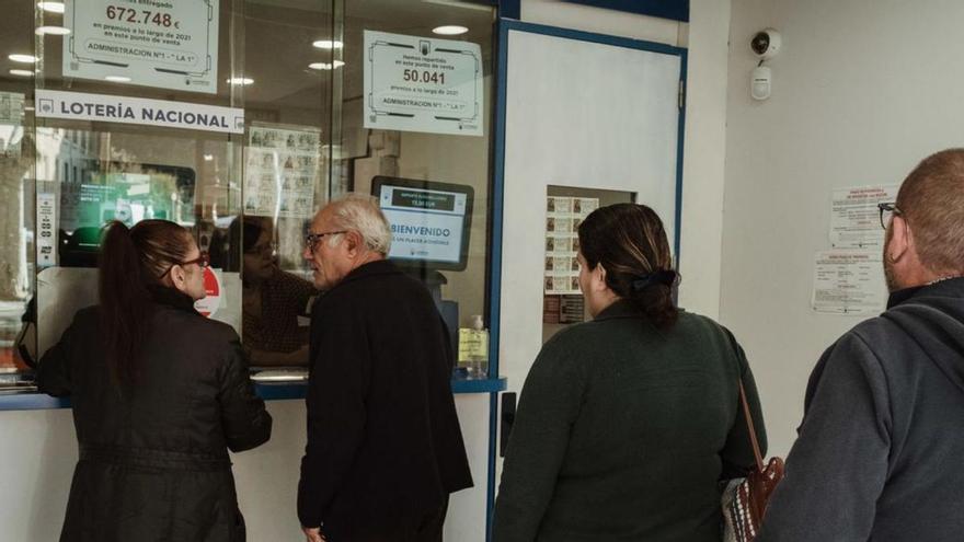 Varias personas hacen cola para comprar lotería de Navidad en una administración de Palma.