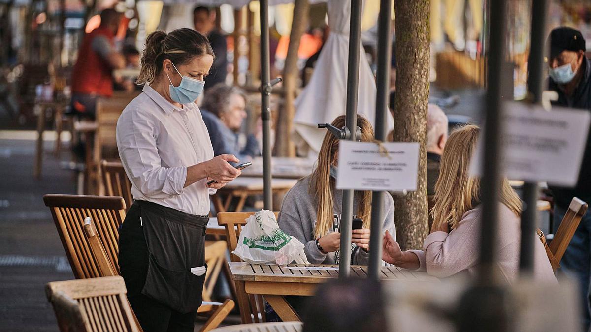 Gente con mascarilla en una terraza.