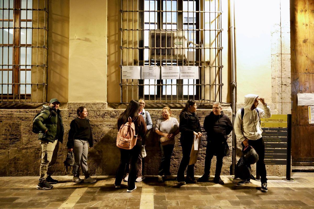 Un grupo de personas haciendo cola de noche ante las oficinas municipales para obtener los documentos necesarios para la regularización
