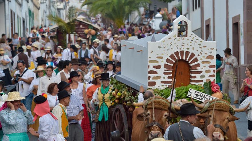 Debajo, el alcalde, Juan Ramón Martín, ayuda a un romero a descargar los productos de la tierra ante la imagen de la patrona, que aguardaba a las puertas de la iglesia.