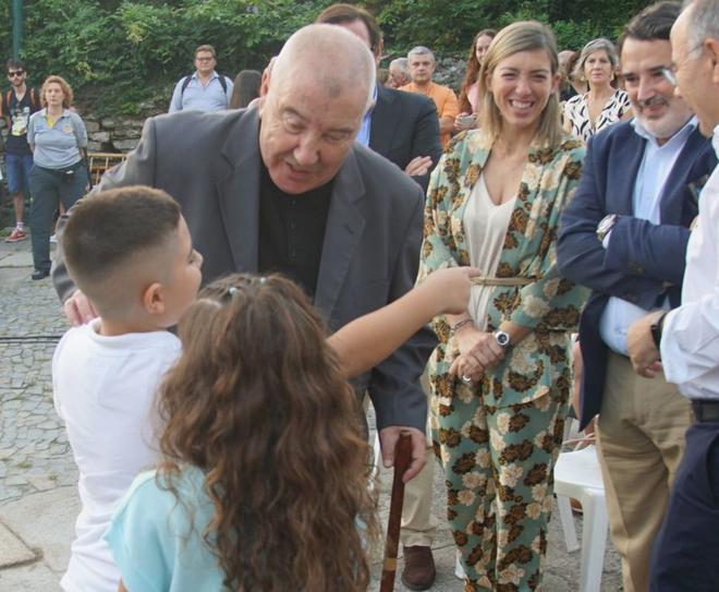 El sacerdote saluda a dos niños en la plaza de la Colexiata