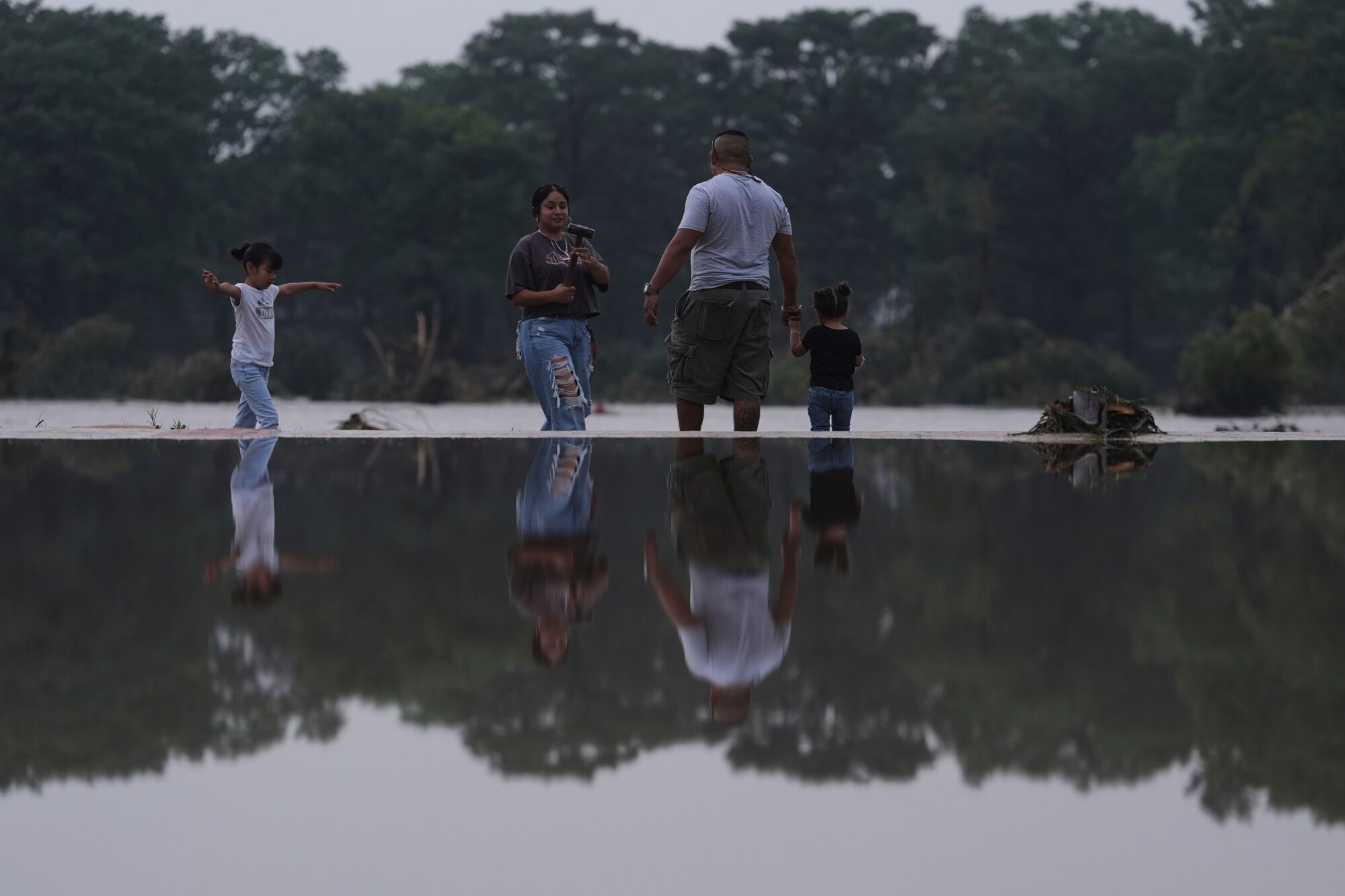 Ernesto Salazar, second from right, and his family survey damage caused along the Guadalupe River after a flash flood swept through the area, Friday, July 4, 2025, in Kerrville, Texas. (AP Photo/Eric Gay)