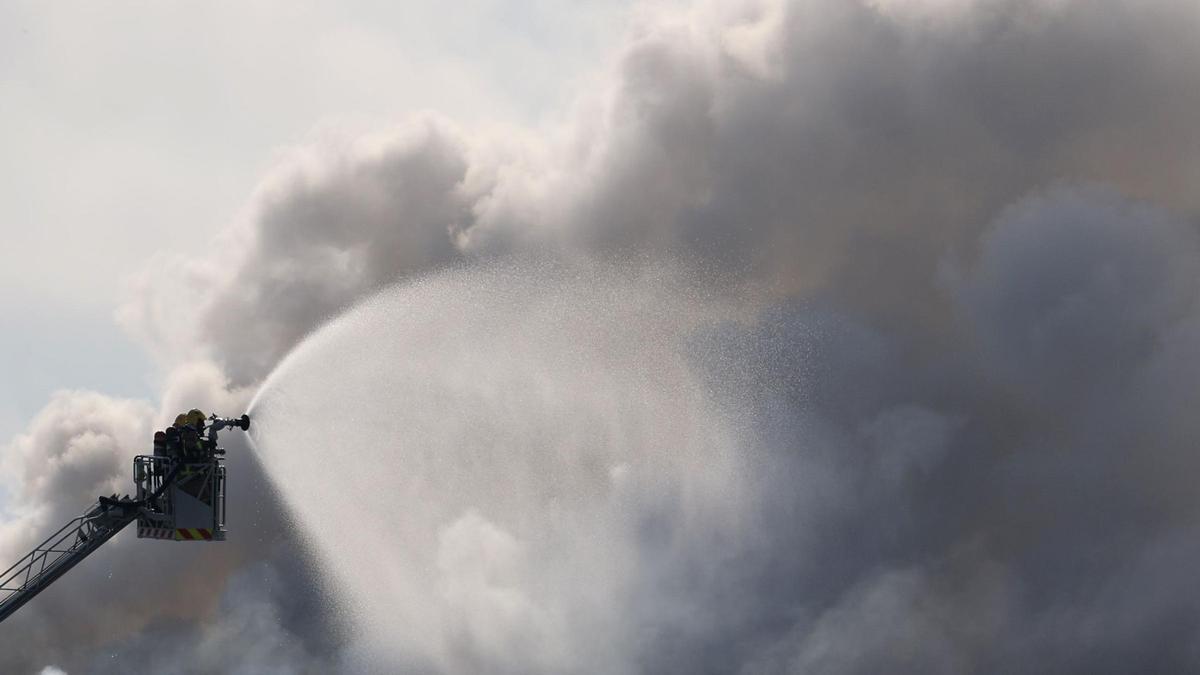 Unos bomberos tratan de extinguir el incendio tóxico en la empresa siniestrada en Vilanova i la Geltrú.
