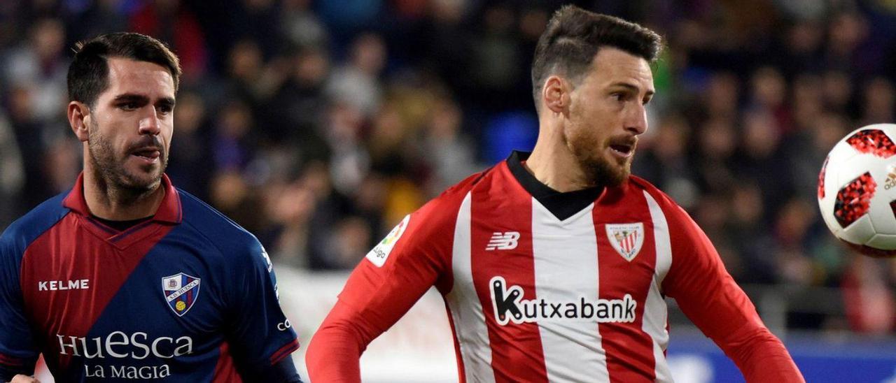 Pablo Insua, a la izquierda, presiona a Aduriz en un partido entre Huesca y Athletic de Bilbao. | Javier Blasco