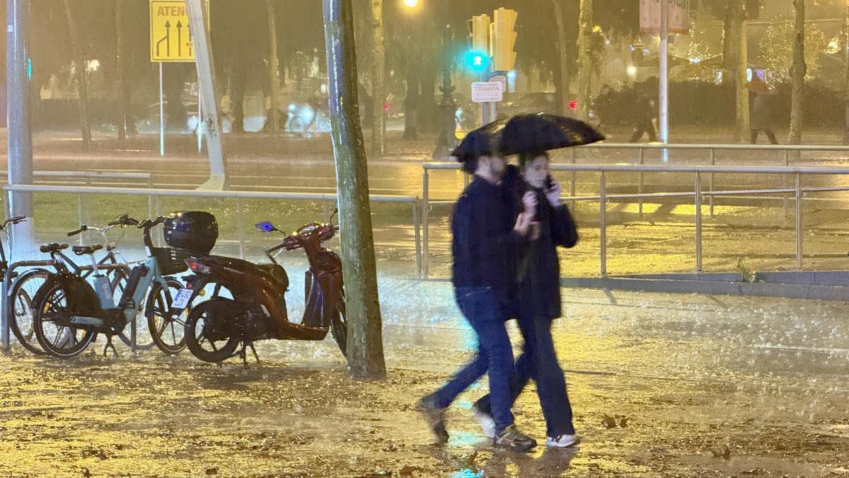 Una parella sota la pluja a l'altura de l'Illa Diagonal, a Barcelona