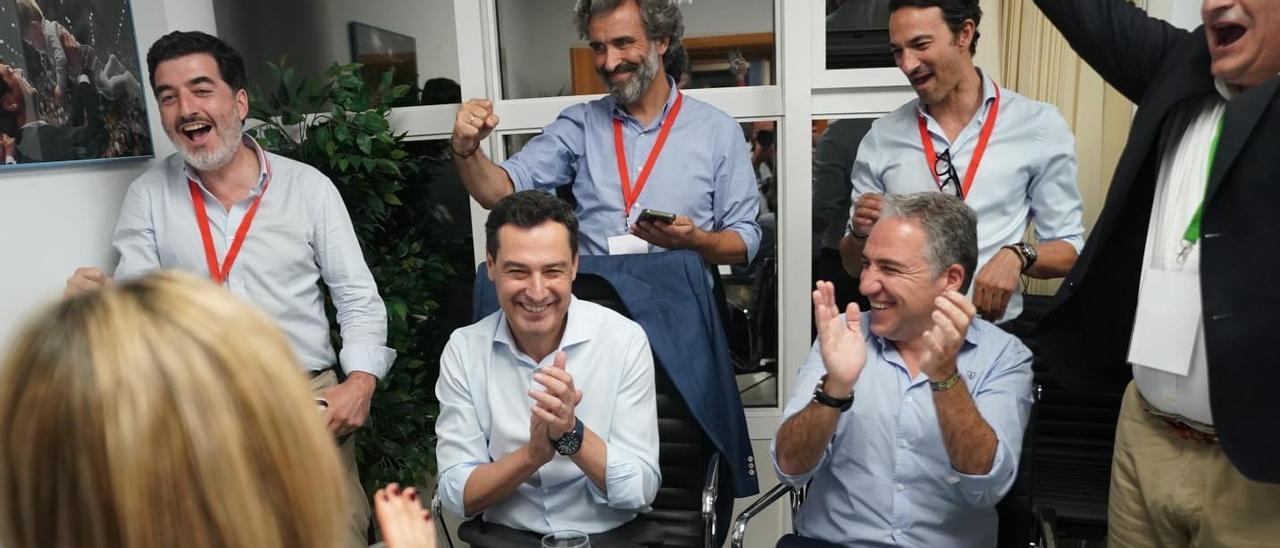 Juanma Moreno y Elías Bendodo celebran la noticia de la mayoría absoluta junto a varios asesores.