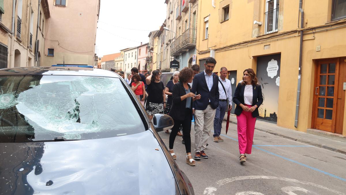 El vicepresident del Govern, Jordi Puigneró, i la consellera de Presidència, Laura Vilagrà, passen per davant d&#039;un cotxe amb els vidres trencats per la pedregada a la Bisbal d&#039;Empordà