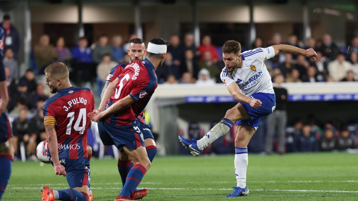 Iván Calero tira a portería ante Loureiro y Jorge Pulido en el último Huesca-Real Zaragoza disputado en El Alcoraz.