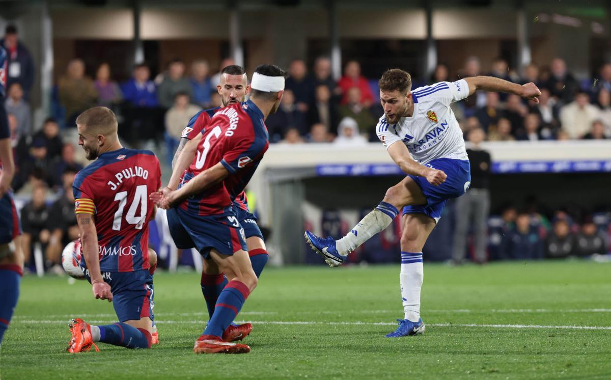 Iván Calero tira a portería ante Loureiro y Jorge Pulido en el último Huesca-Real Zaragoza disputado en El Alcoraz.
