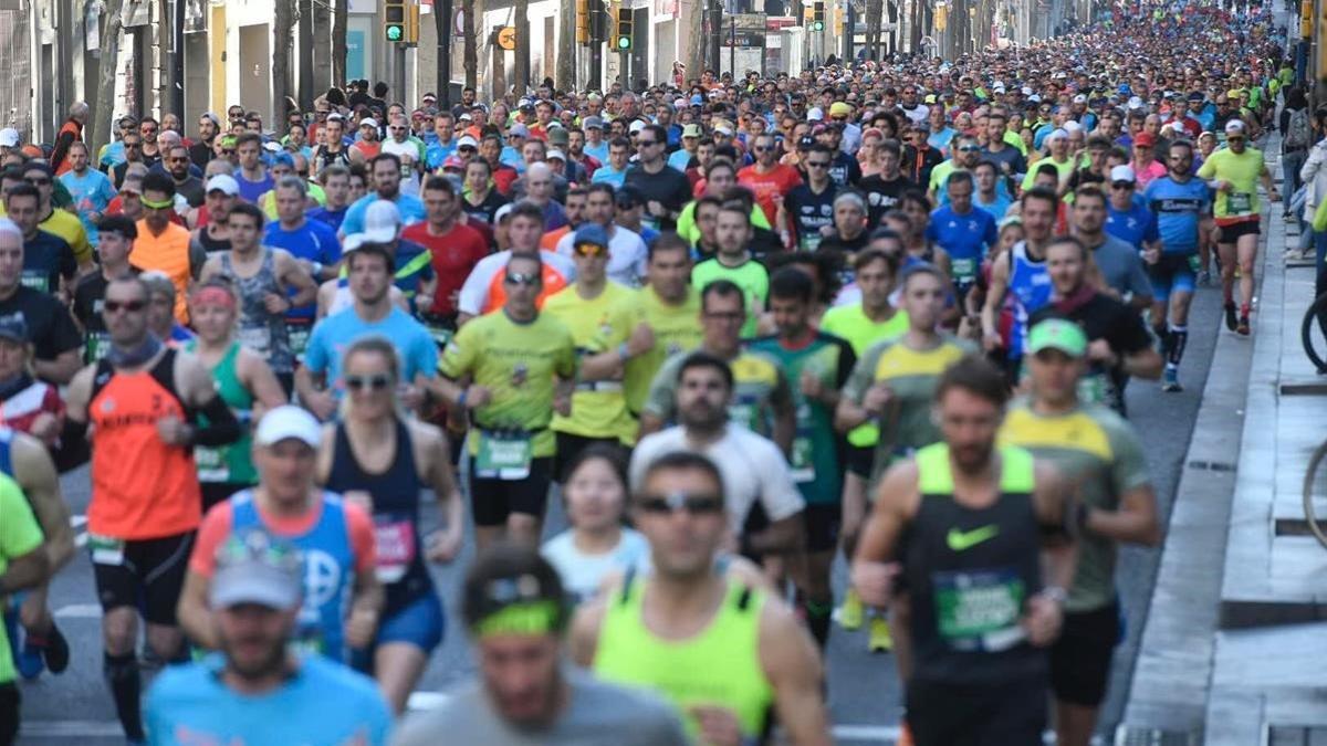 Miles de corredores del maratón a su paso por la carretera de Sants.