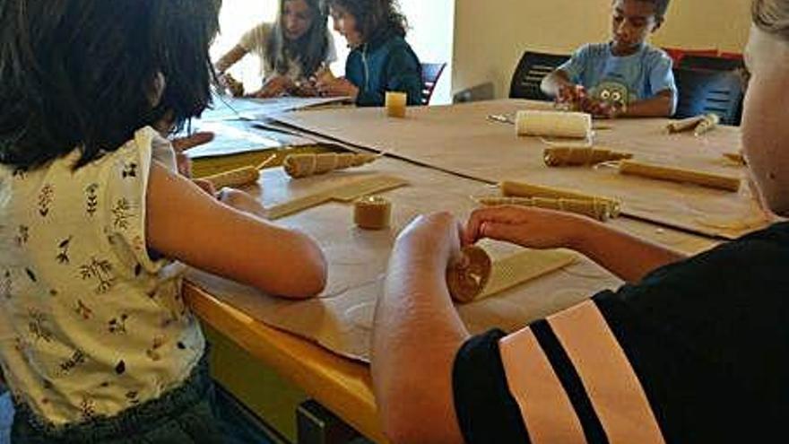 Los niños se entretienen convirtiendo las láminas de cera en velas.