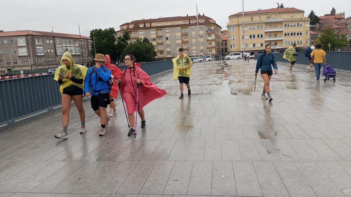 Peregrinos, este jueves su paso por el puente de O Burgo durante las lluvias de la mañana.