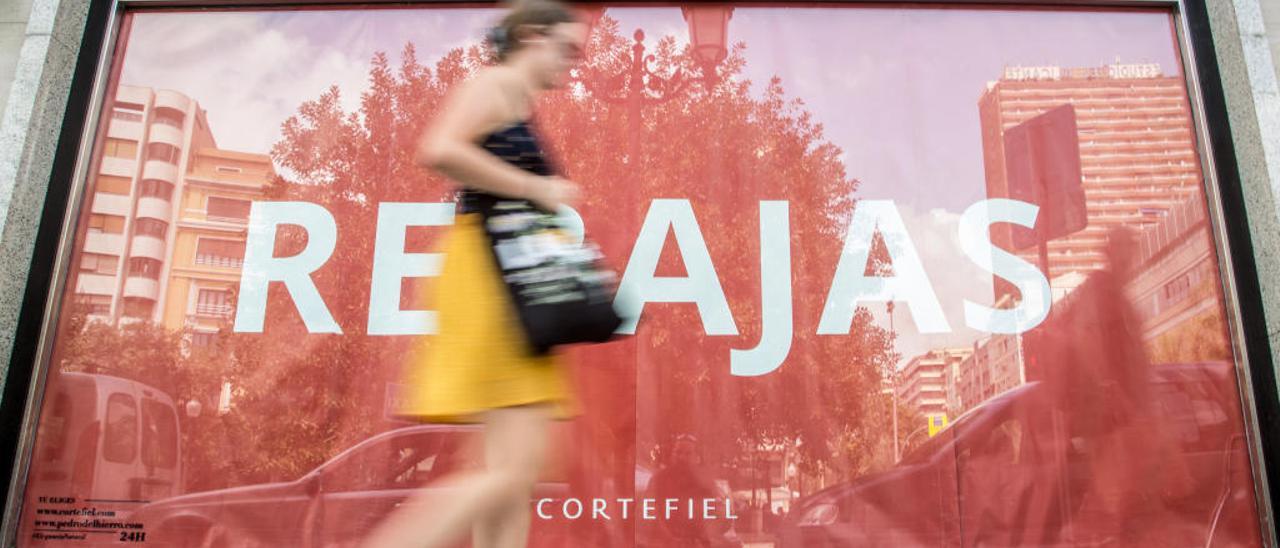 Una mujer pasa por delante de un cartel anunciador de un reciente periodo de rebajas en Alicante, en imagen de archivo.