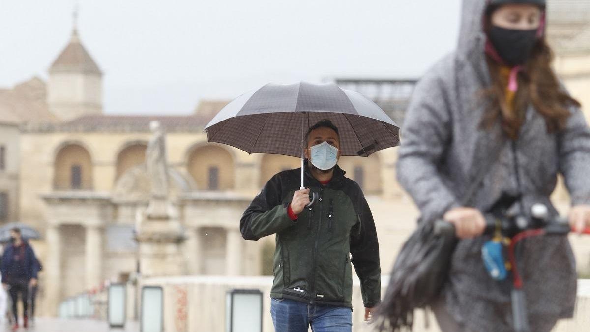 Viandantes protegidos de la lluvia en el Puente Romano de Córdoba.