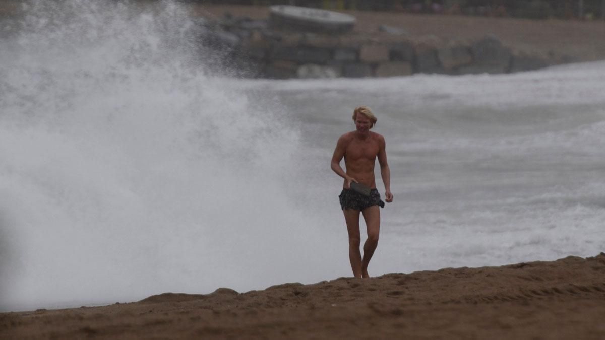 Surferos en la playa de la Barceloneta, en un día lluvioso.