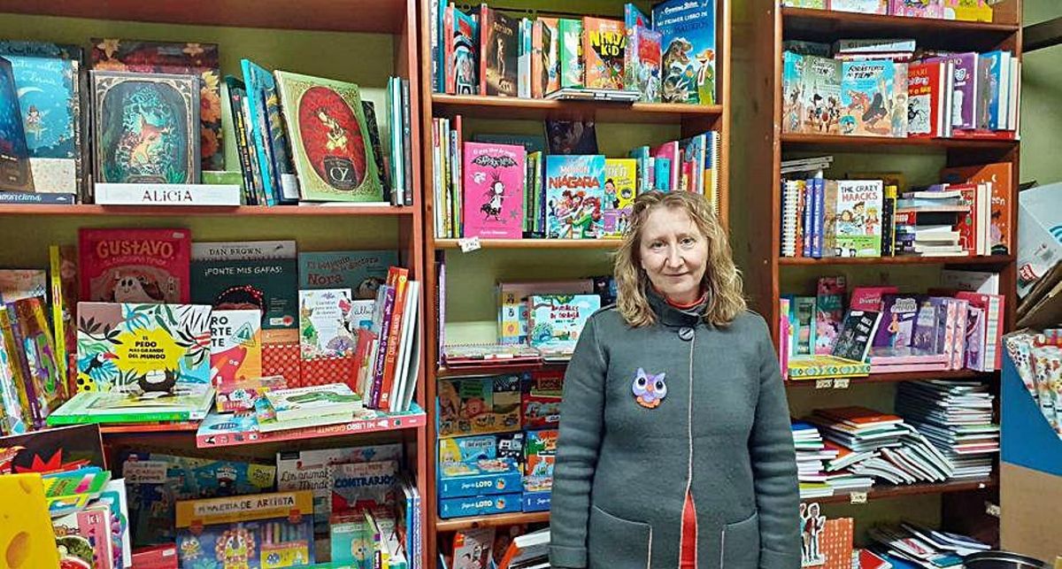 Varias personas hacen cola frente a una juguetería (arriba)Carmela Reguilón, en su negocio (abajo). | C. G. R.