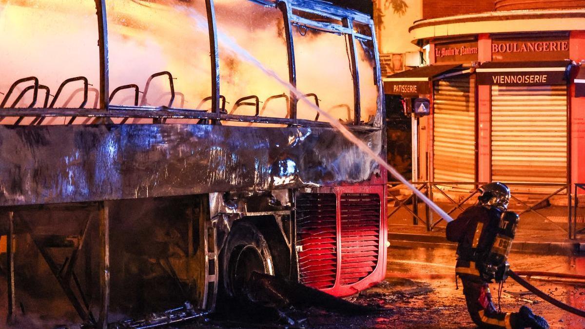 Cuarta noche de disturbios en Francia. Los bomberos extinguen el fuego en un autobús incendiado en Nanterre.
