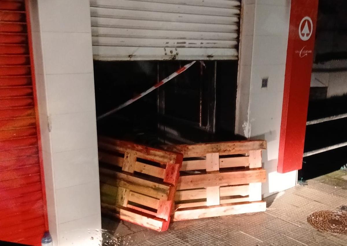 Los autores colocaron palés para sujetar la verja de entrada al supermercado.