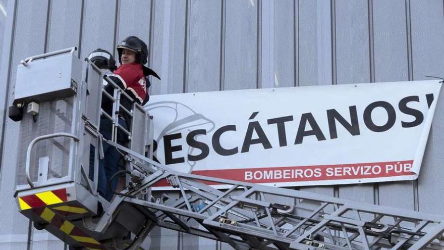 Bomberos instalan una pancarta con el lema &#039;Rescátanos&#039;.