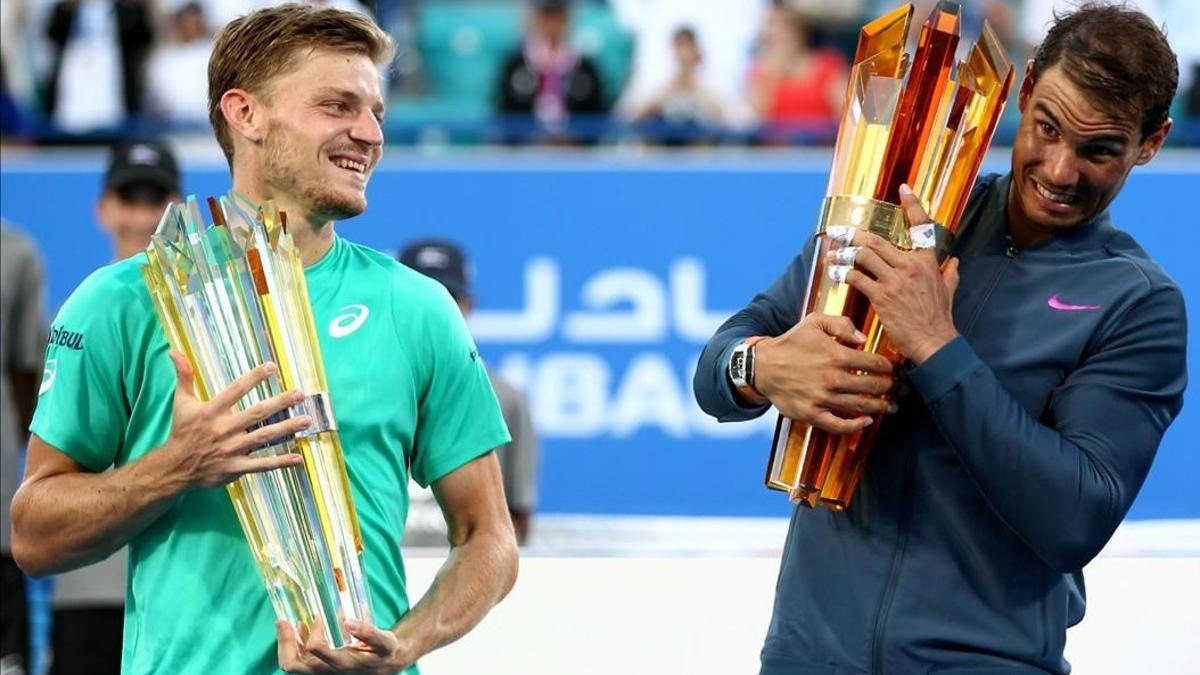 Goffin y Nadal muestran sus trofeos tras la final de Abu Dabi, ganada por el mallorquín.