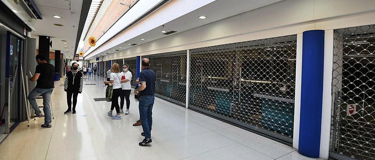 Varios vecinos, ayer, ante el local vació en el Centro Comercial A Barca.   | // GUSTAVO SANTOS