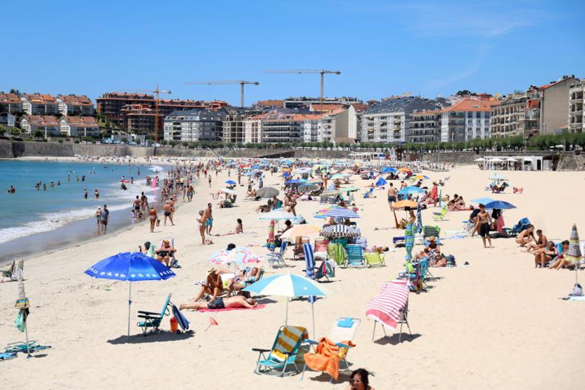 La playa de Silgar, en Sanxenxo, con los edificios residenciales en primera línea de fondo durante el arranque de la temporada de verano.