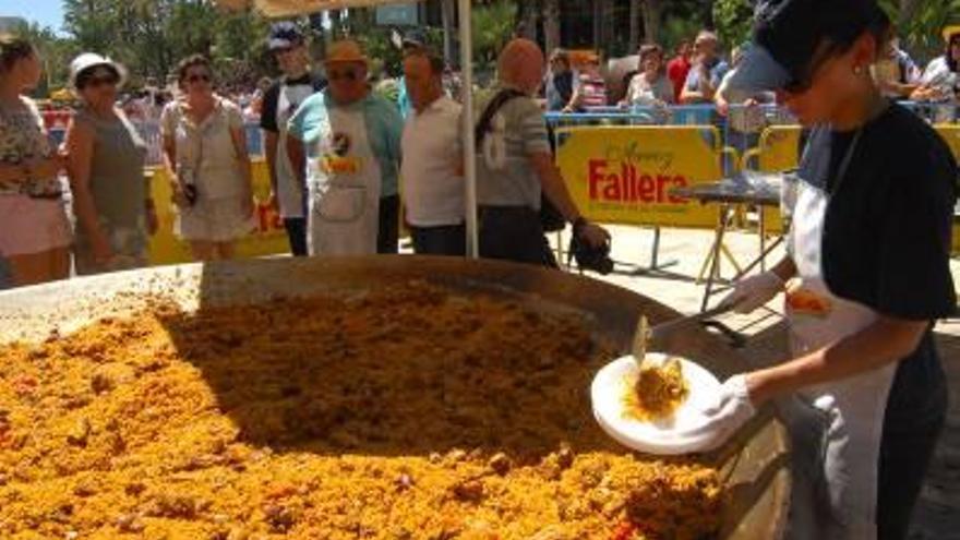 Cientos de personas disfrutan de la paella gigante.