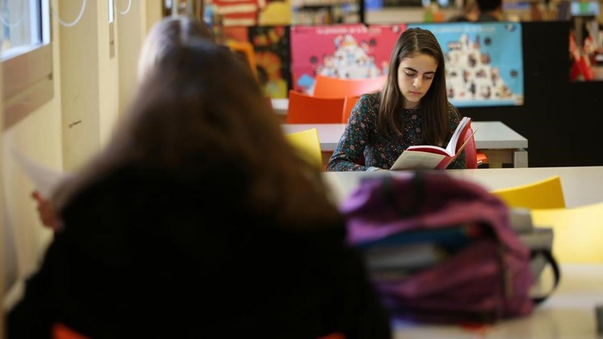 Dos adolescentes leen libros en la biblioteca de Poblenou Manuel Arranz