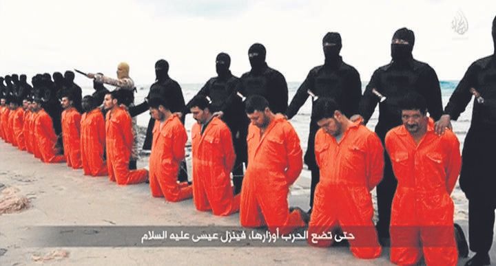 Varios cristianos egipcios de rodillas delante de hombres del EI armados