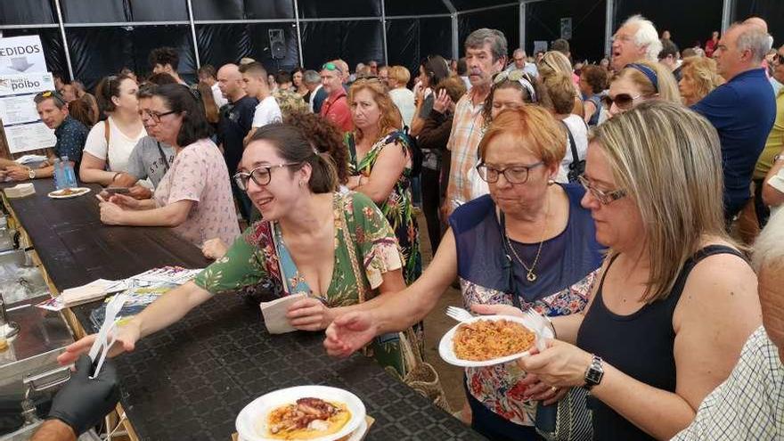 Varias asistentes recogen sus raciones de uno de los puestos de la Festa do Polbo. // Santos Álvarez